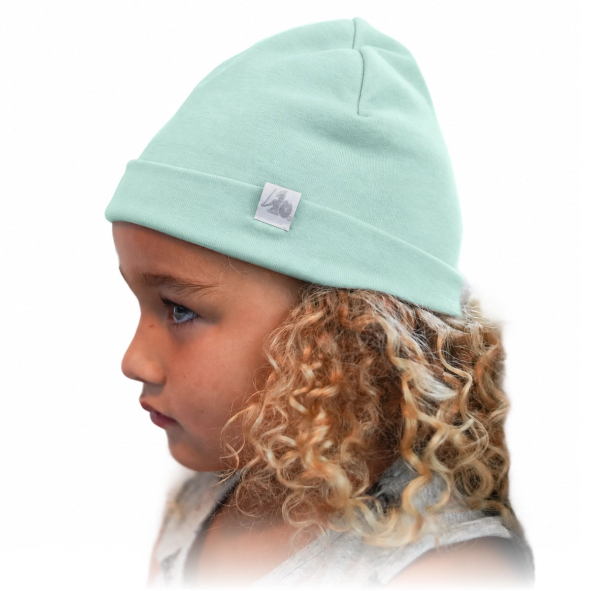 Young girl wearing a seafoam green DefenderShield EMF protection beanie with a soft knit texture, folded cuff and logo patch.